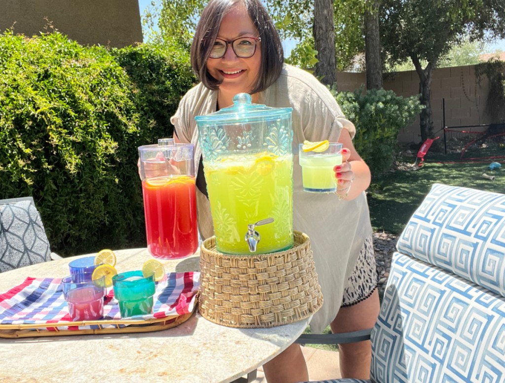 Woman at a backyard party standing with a beverage next to her Better Homes and Gardens Beverage Dispenser Stand