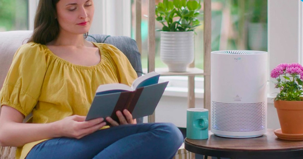 Bissell MYAir Personal Air Purifier on a table while a woman is reading
