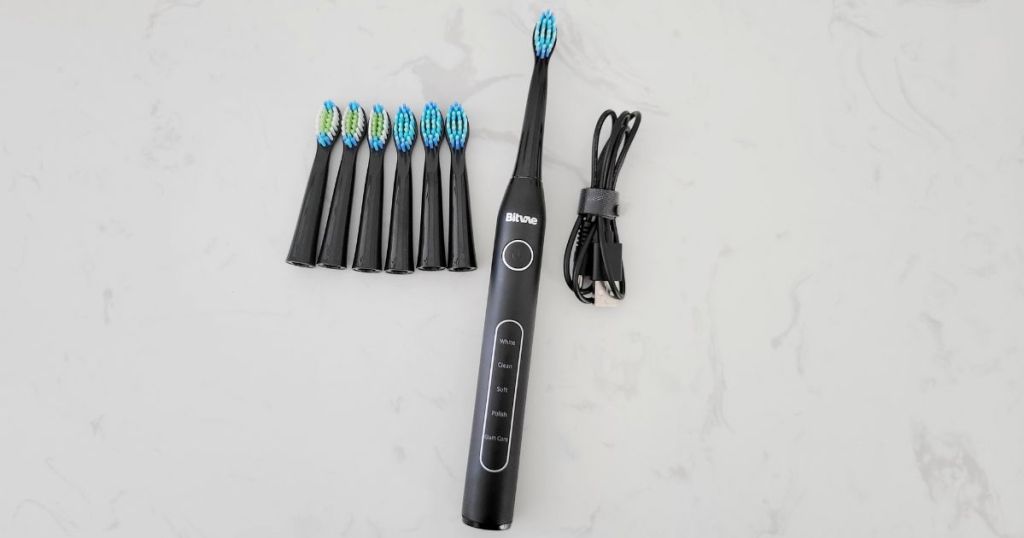 black Bitvaie electric toothbrush with cord and 6 brush heads next to it