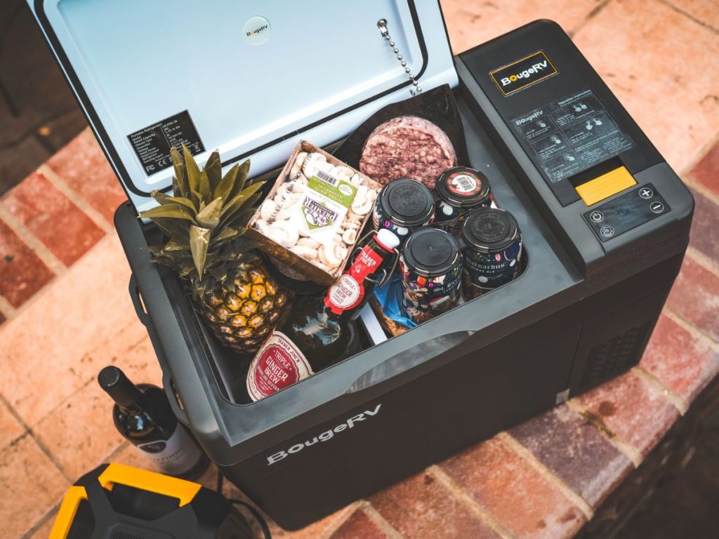 Portable fridge with food in it and a wine bottle next to it