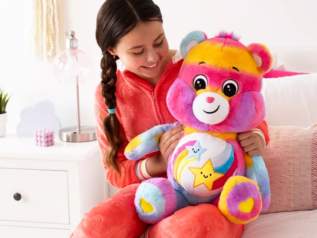 girl holding a large rainbow care bear