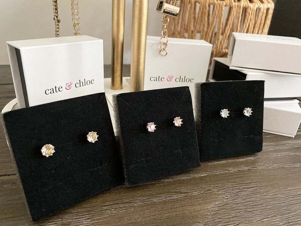 three pairs of stud earrings leaning against white gift boxes