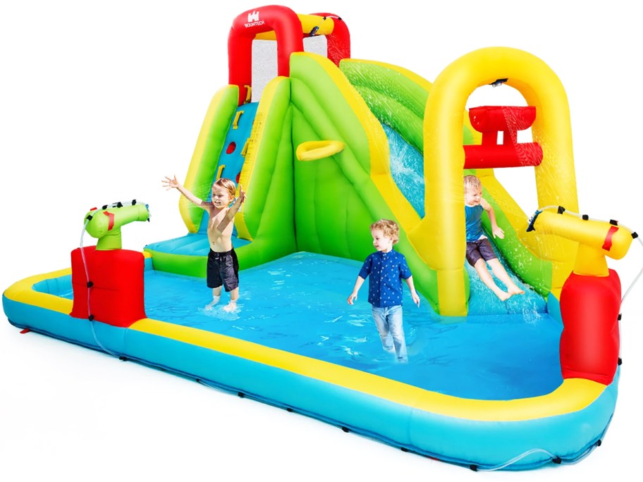 three kids playing on giant inflatable water slide