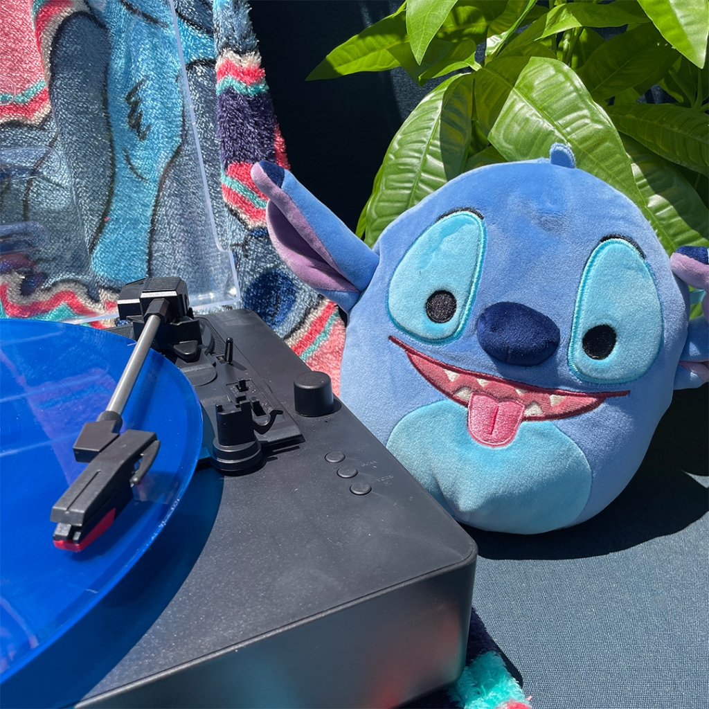 Disney Squishmallows Stitch sitting by a record player