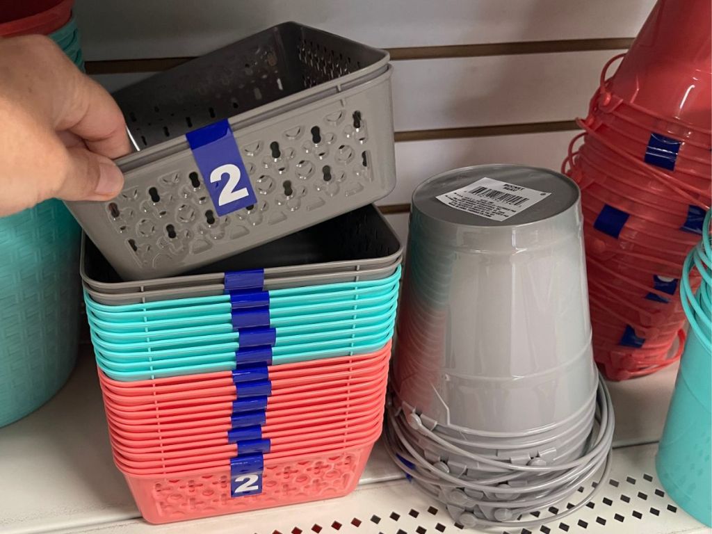 Hand picking up a set of small storage baskets at Dollar Tree
