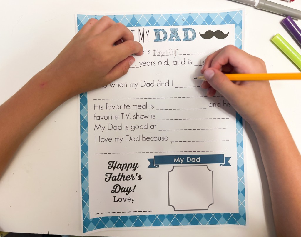 child filling out a Free Father's Day Printable which he is using as one of his free fathers day cards