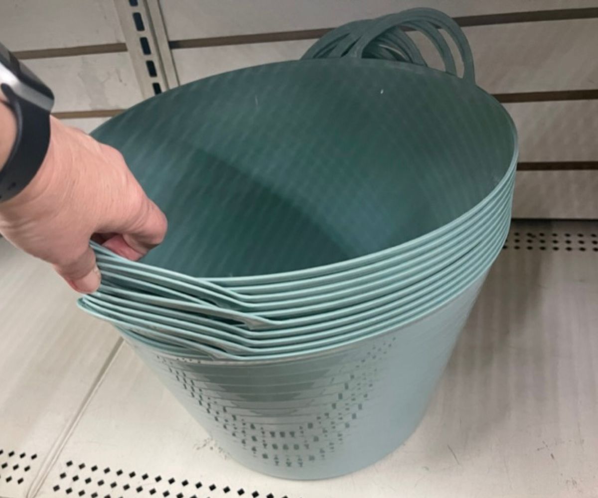 a womans hand grabbing a sage green Plastic Storage Tubs