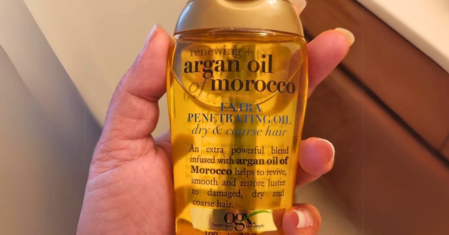 hand holding a bottle of OGX Renewing + Argan Oil Treatment