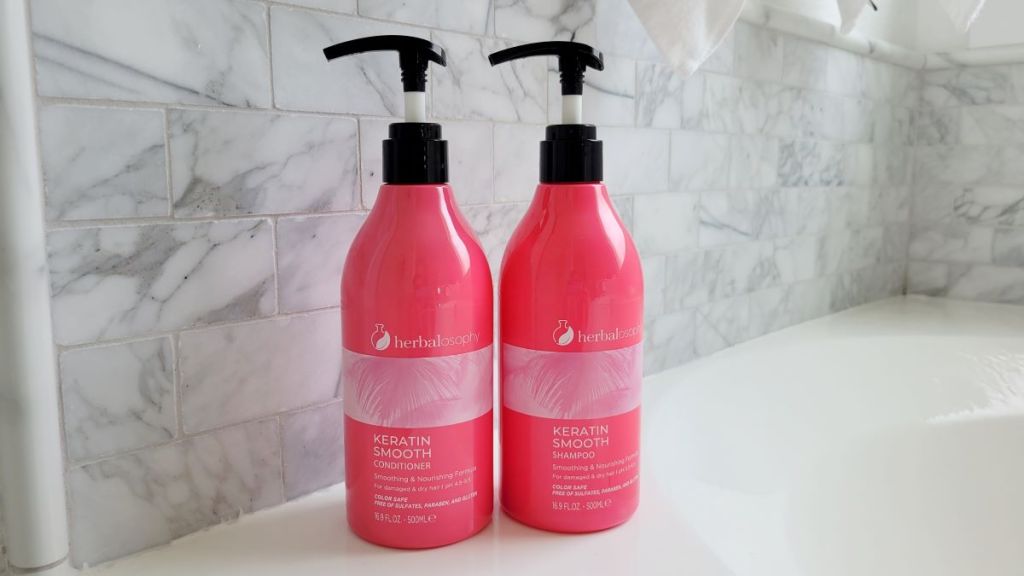 Pink shampoo and conditioner bottles next to a bathtub