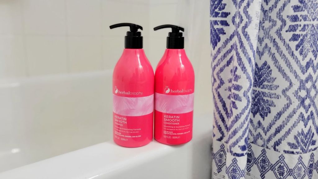 Pink shampoo and conditioner bottles next to a bathtub