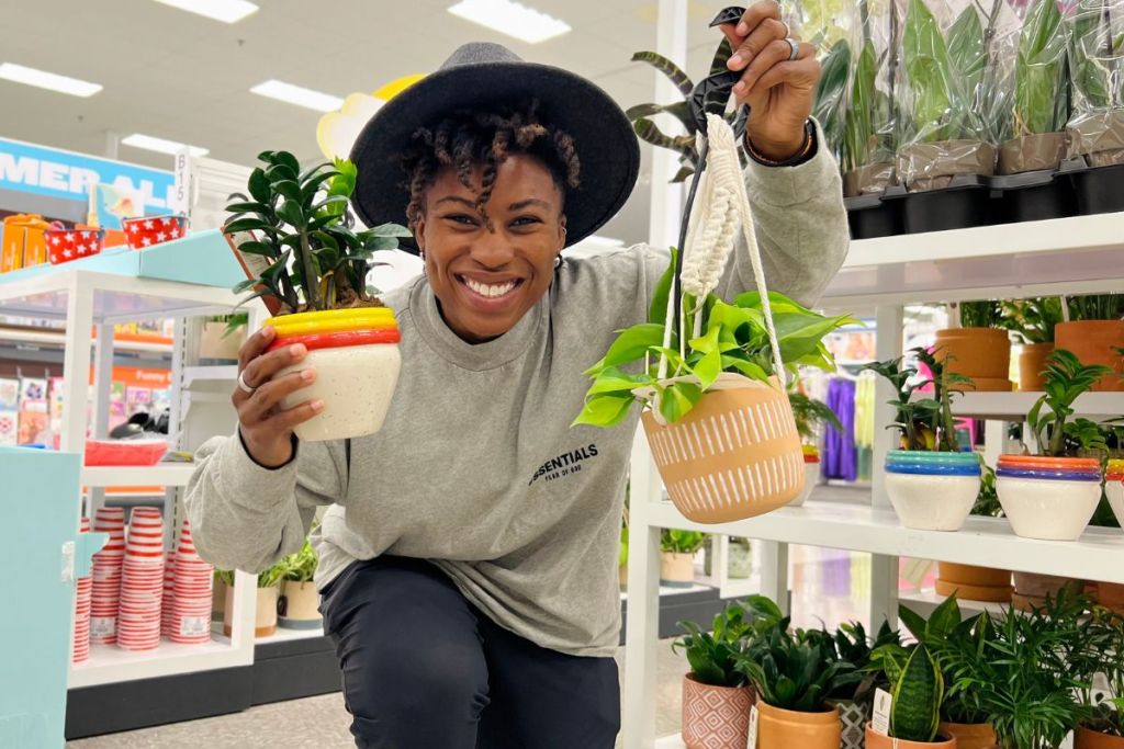 Camm holding 2 live plants and standing in front of live plants on sale display at Target