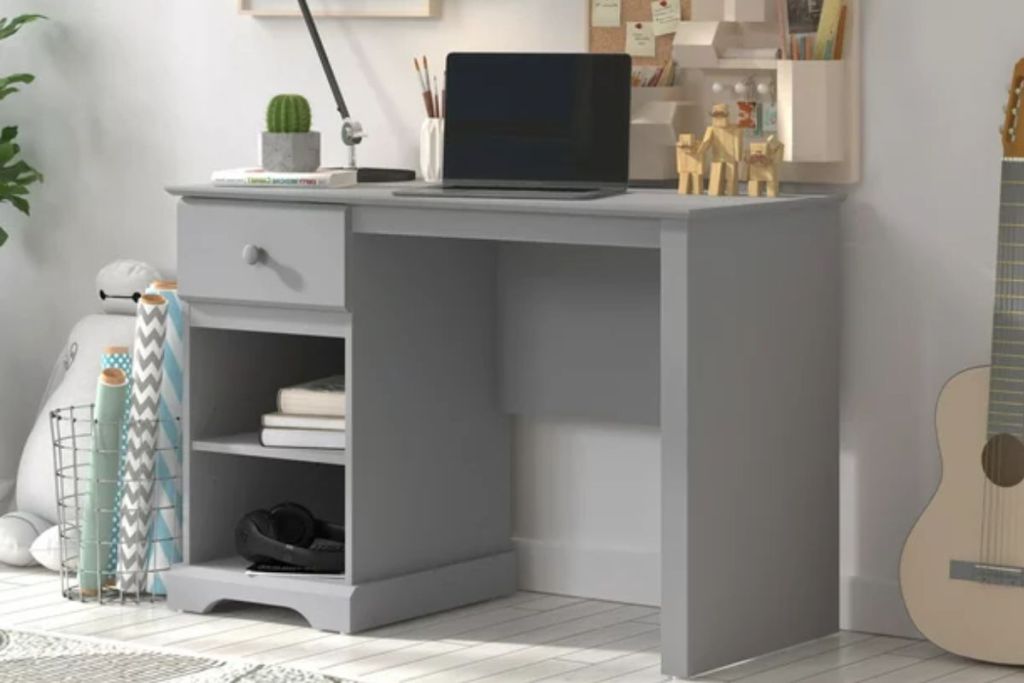 Campbell Wood Kids Desk with 1 Drawer and 2 Shelf Storage, Gray shown with laptop and office supplies in a bedroom