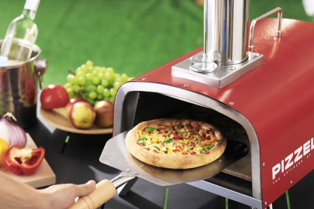 PIZZELLO Stainless Steel Freestanding Pizza Oven Red shown with a man's hand pulling a pizza out of it