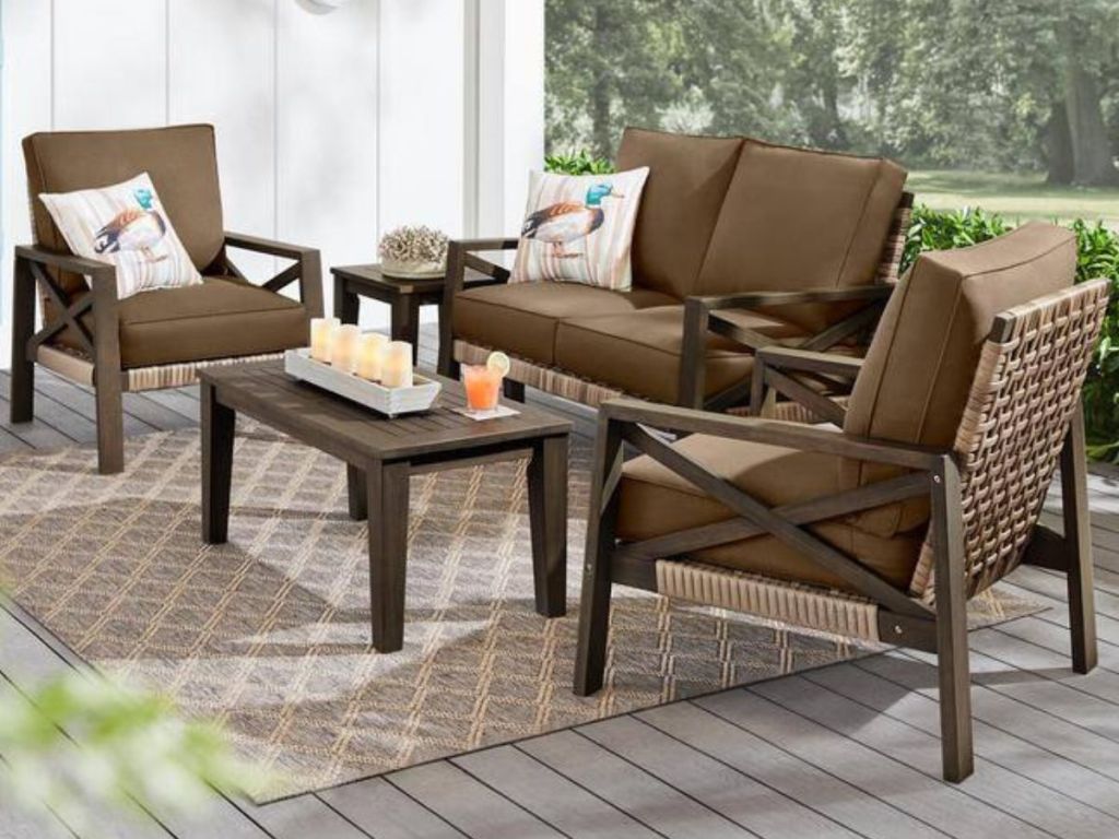 4 piece brown wicker patio set with couch, 2 chairs and a coffee table