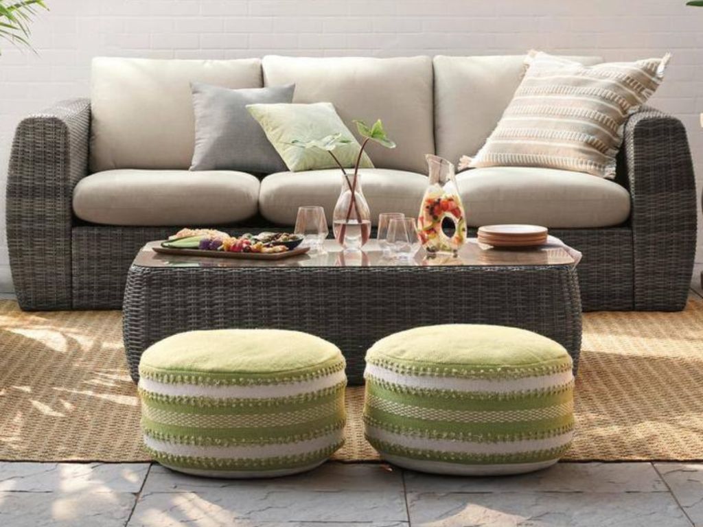 wicker outdoor couch with cushions with a coffee table and seating poufs in front of it