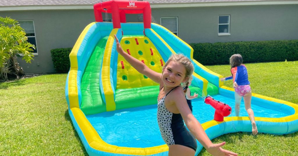 2 girls playing in inflatable water park in backyard