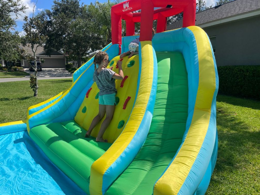 inflatable water park in backyard with girl doing rockwall