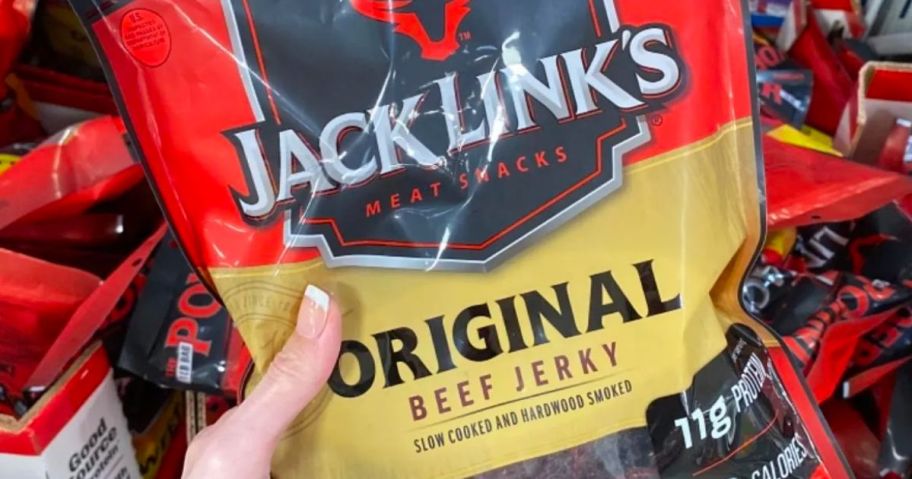 a womans hand holding a bag of Jack links beef jerky