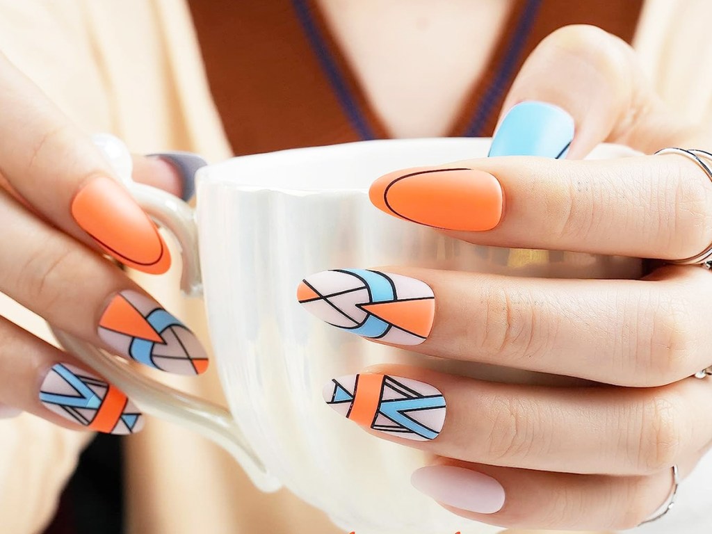 woman holding a mug with blue and orange press-on nails