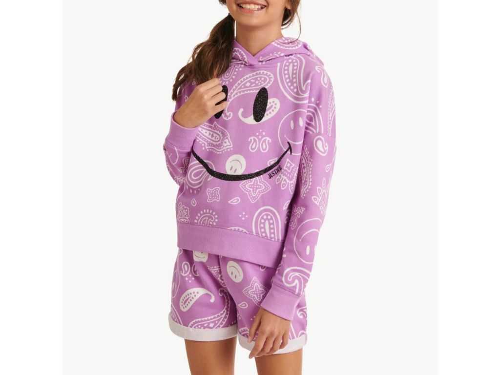 a girl wearing a purple sweatsuit with a smile on it 