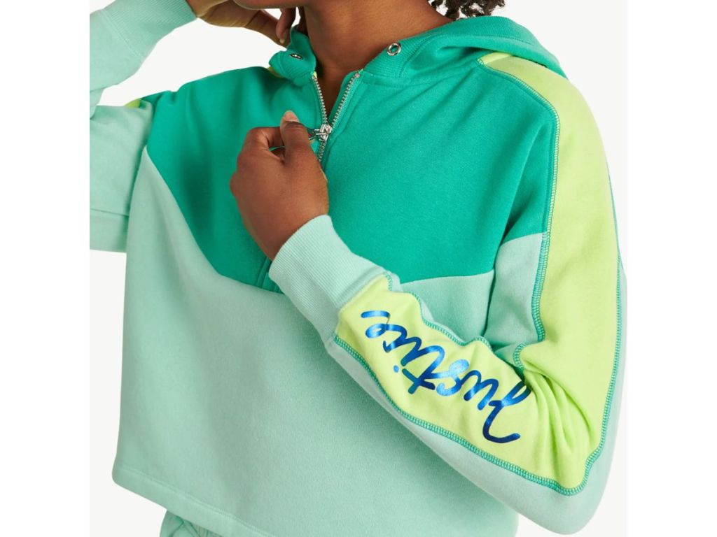 a girl wearing a teal and yellow zipped hoodie