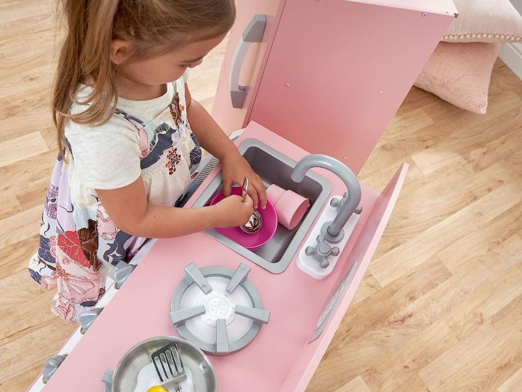 girl playing with pink kitchen set 