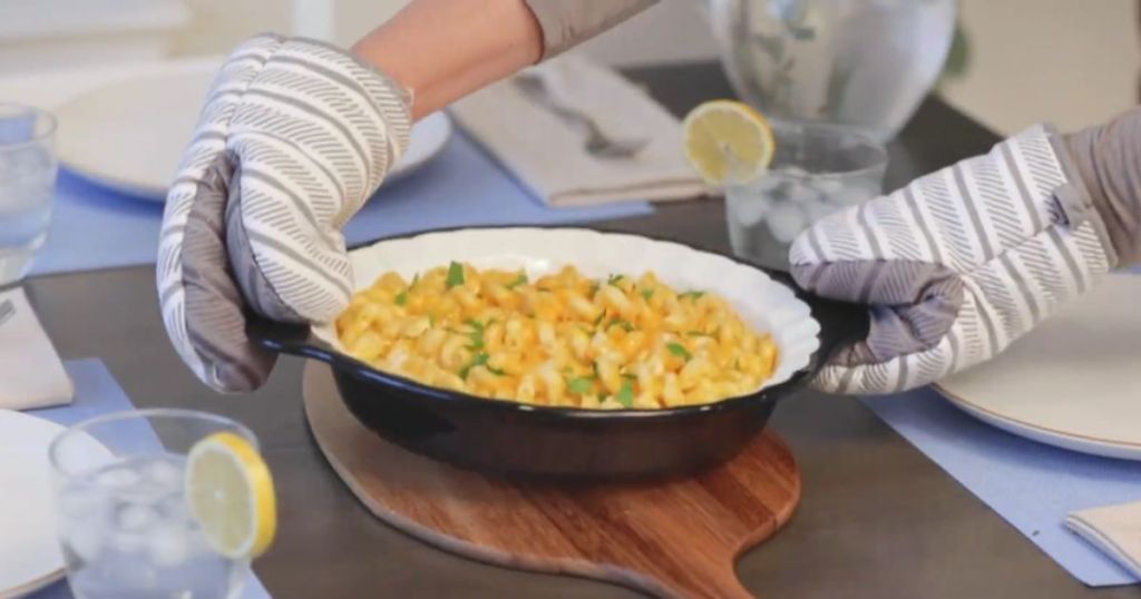 Hand wearing oven mits placing a pie plate of eggs on a table