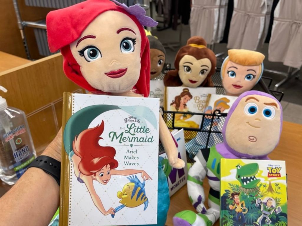 Kohl's Cares Disney Plush with hand holding an ariel doll in front of Tiana, Belle, Cinderalla and Buzz Lightyear