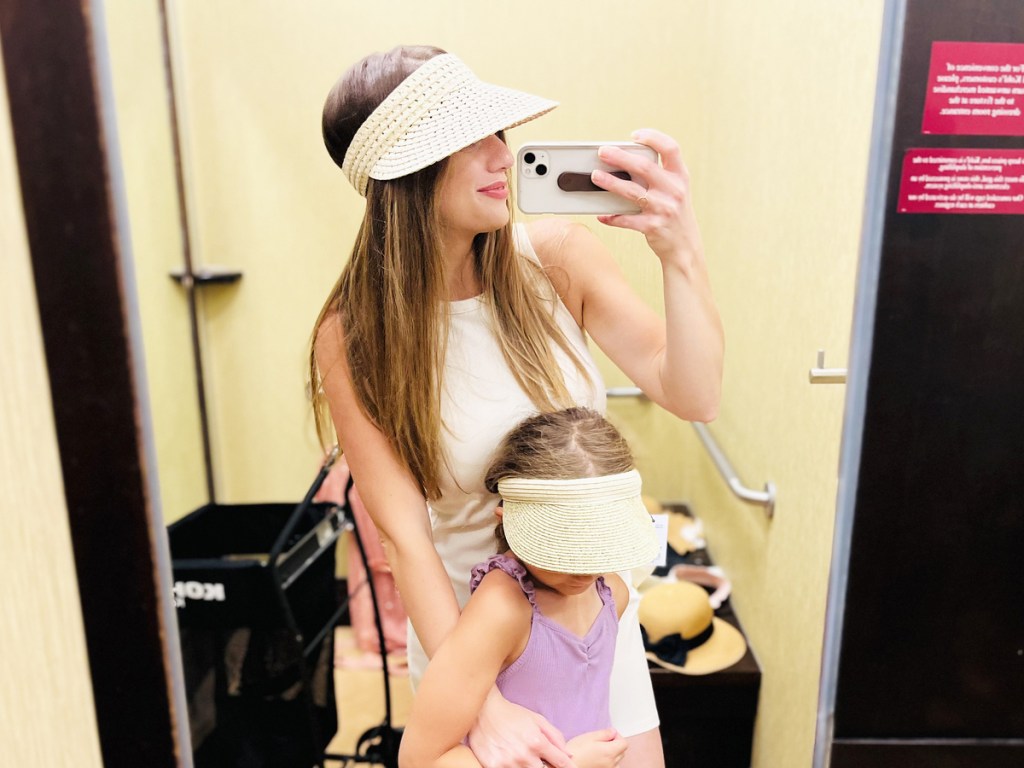 woman and daughter trying on visors in dressing room mirror