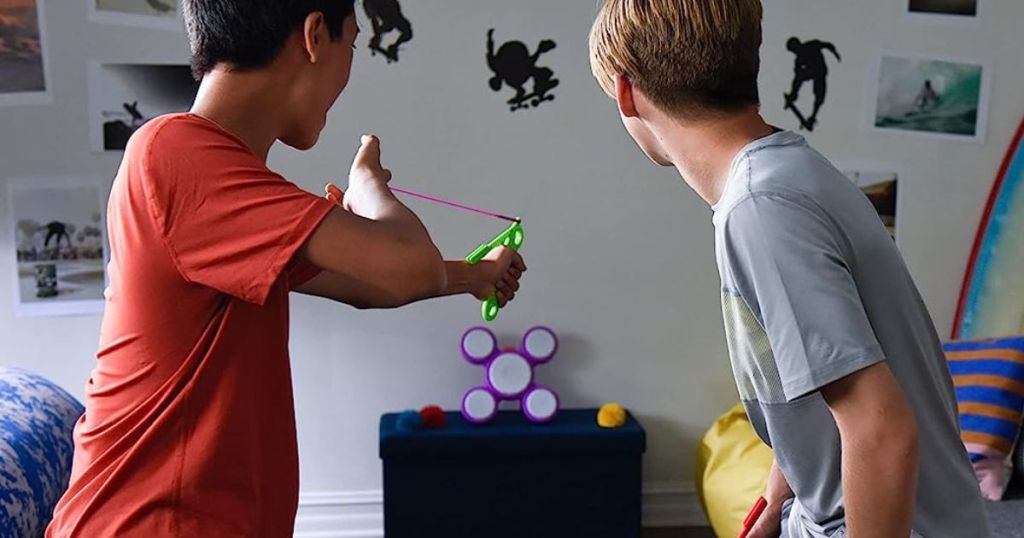 Two boys playing a Koosh sharp shot game in a bedroom