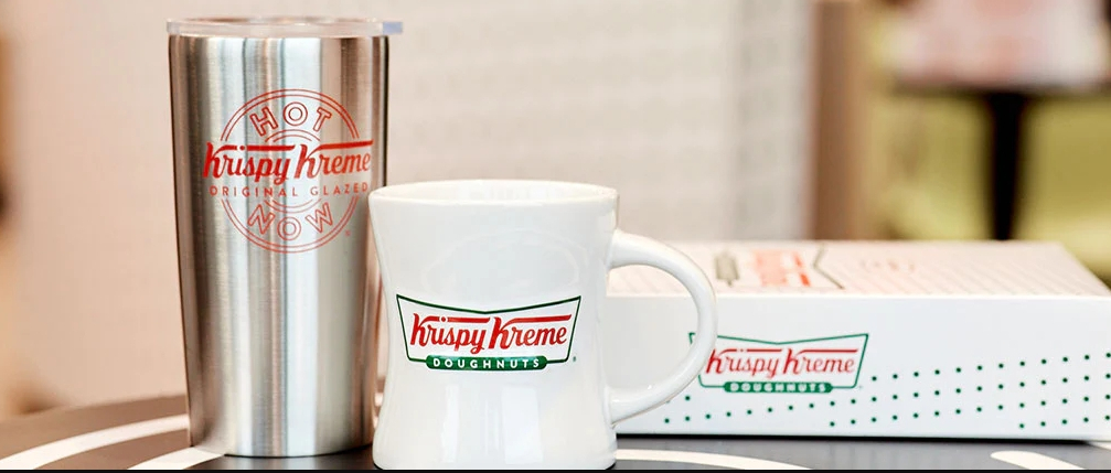 Two Krispy Kreme mugs next to a box of donuts