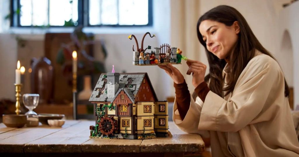person building LEGO Disney Hocus Pocus: The Sanderson Sisters' Cottage 