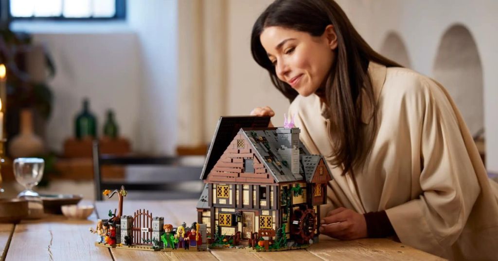 person building LEGO Disney Hocus Pocus: The Sanderson Sisters' Cottage 