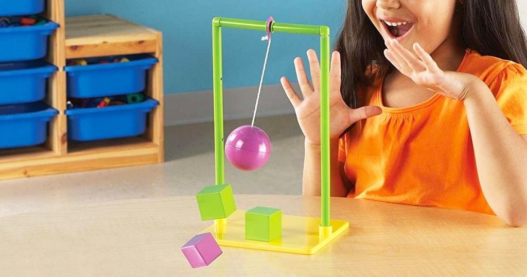 girl playing with pendulum toy on a table