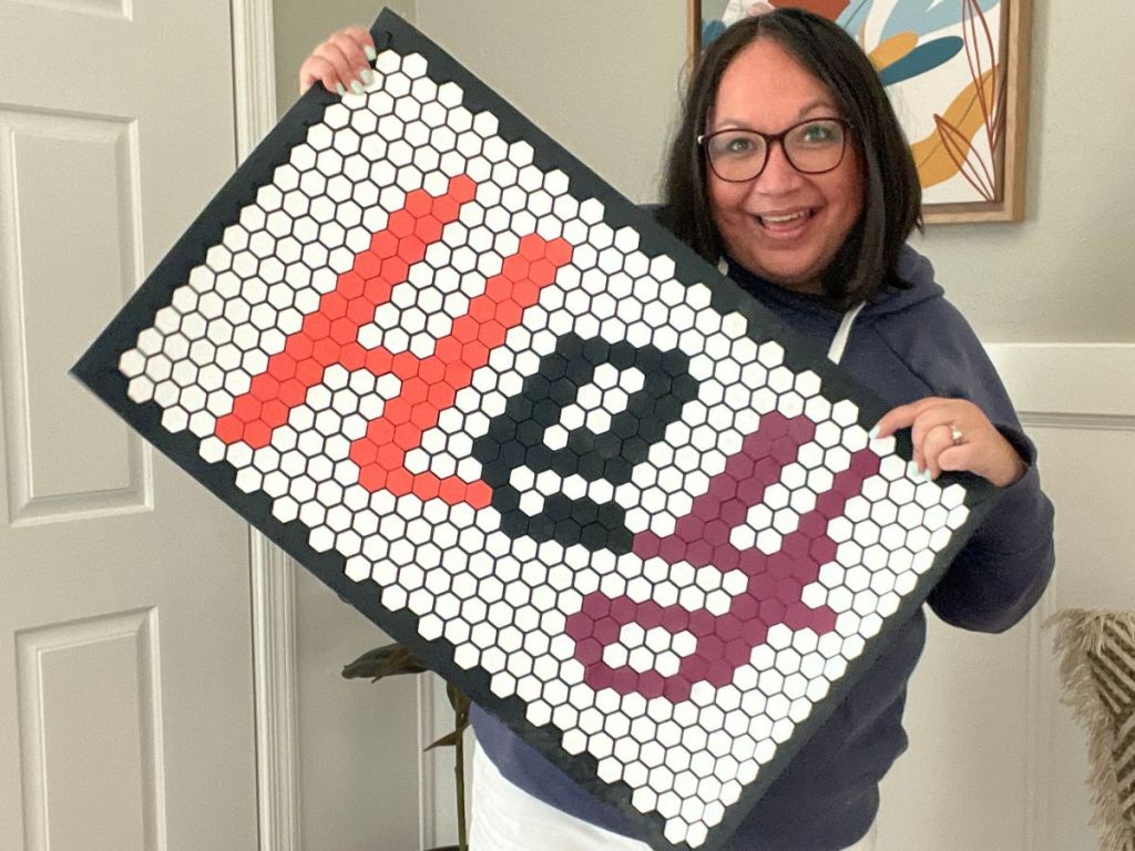 Woman holding up a Letterfolk's Tile Mat that says "Hey" on it