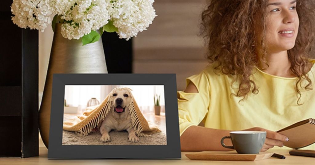 woman sitting at table with coffee cup next to digital smart picture frame
