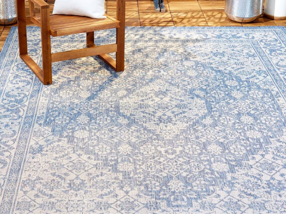 blue and white patio area rug with wood chair on top