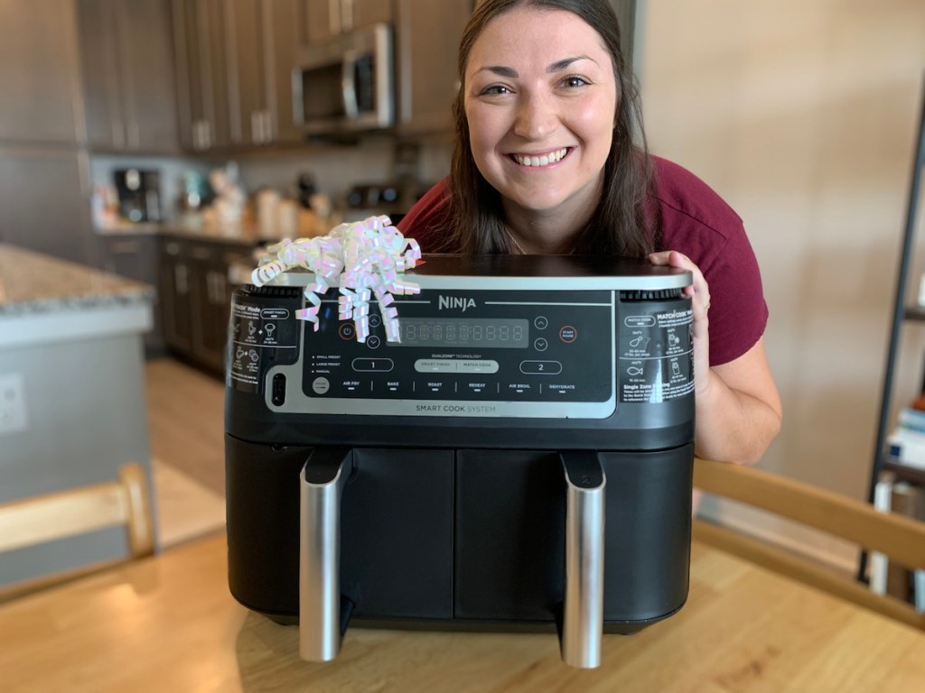 woman holding the back of ninja foodi air fryer with white bow on top