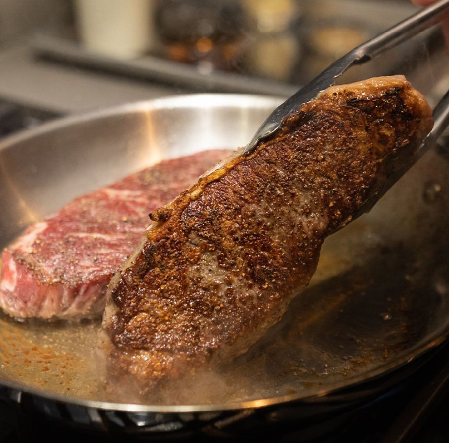 An Omaha Steaks Strip steak being seared in a pan
