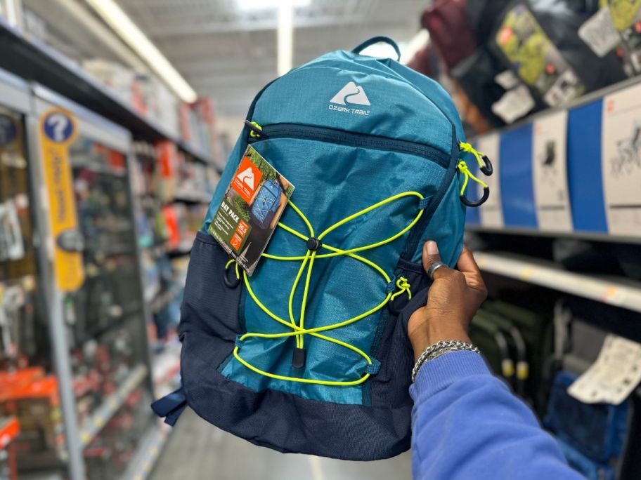 A person holding a blue backpack in a store