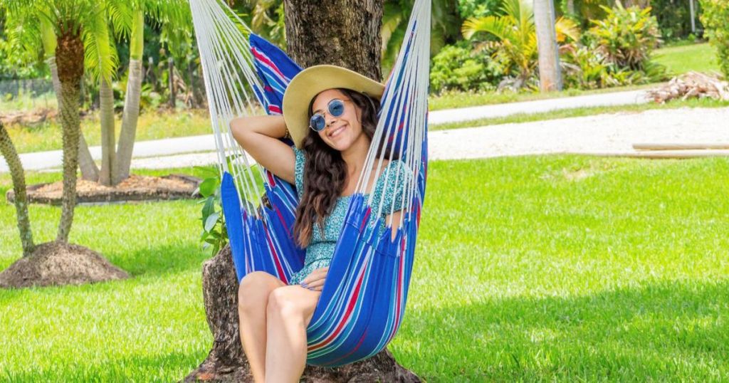 woman sitting on blue and striped hammock 