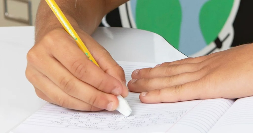child using white pencil cap eraser in notebook