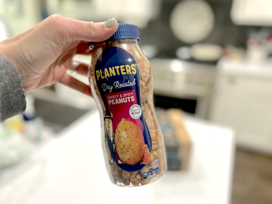 hand holding a bottle of planters sweet and spicy dry roasted peanuts