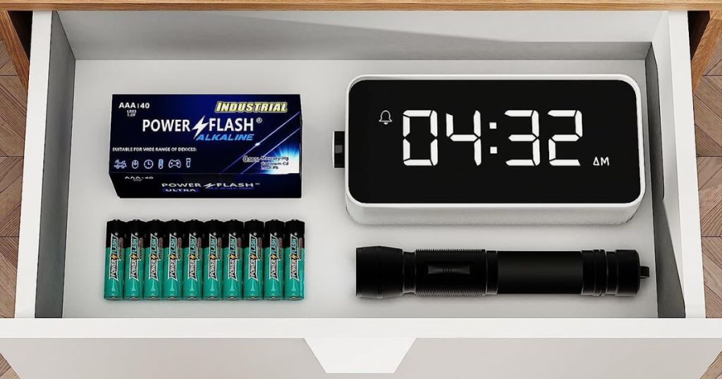 drawer pulled out revealing batteries, clock, and flashlight