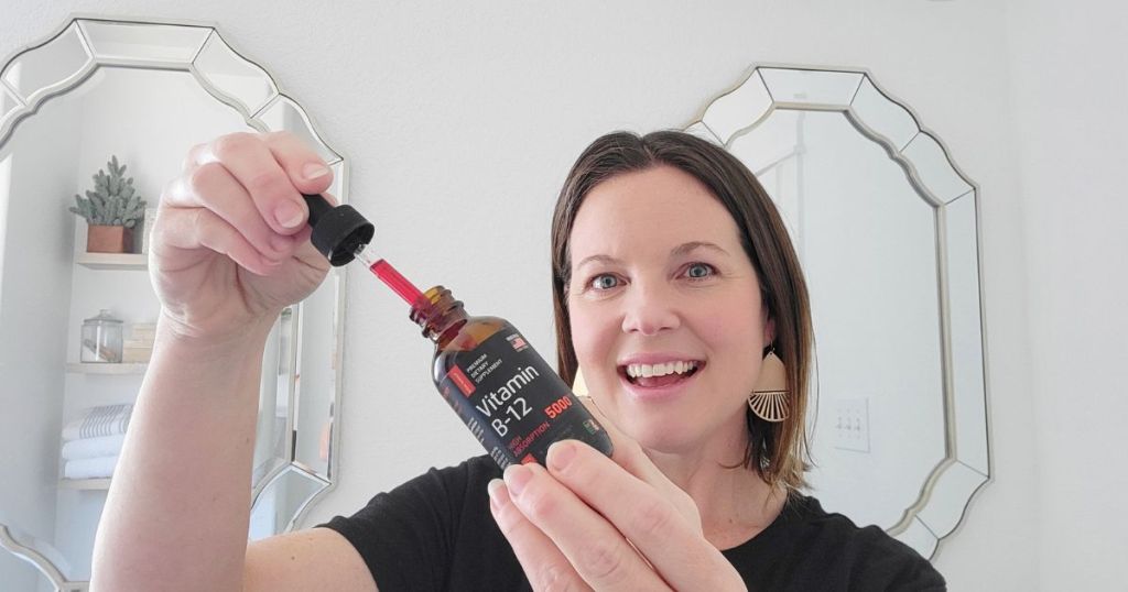 woman pulling dropper with red liquid in it from Vitamin b12 bottle