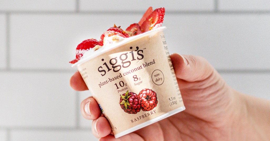 hand holding a cup of Siggi's Coconut Blend Yogurt with strawberries on top