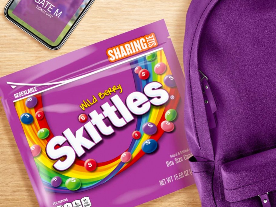 bad of wild berry skittles next to purple backpack