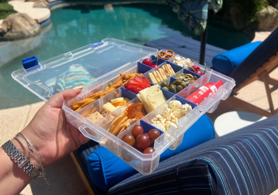 Hand holding out a snackle box near the pool