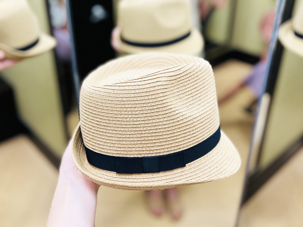 hand holding a white fedora with black bow