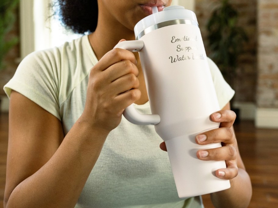 woman sipping from a stanley tumbler that says emotional support water bottle